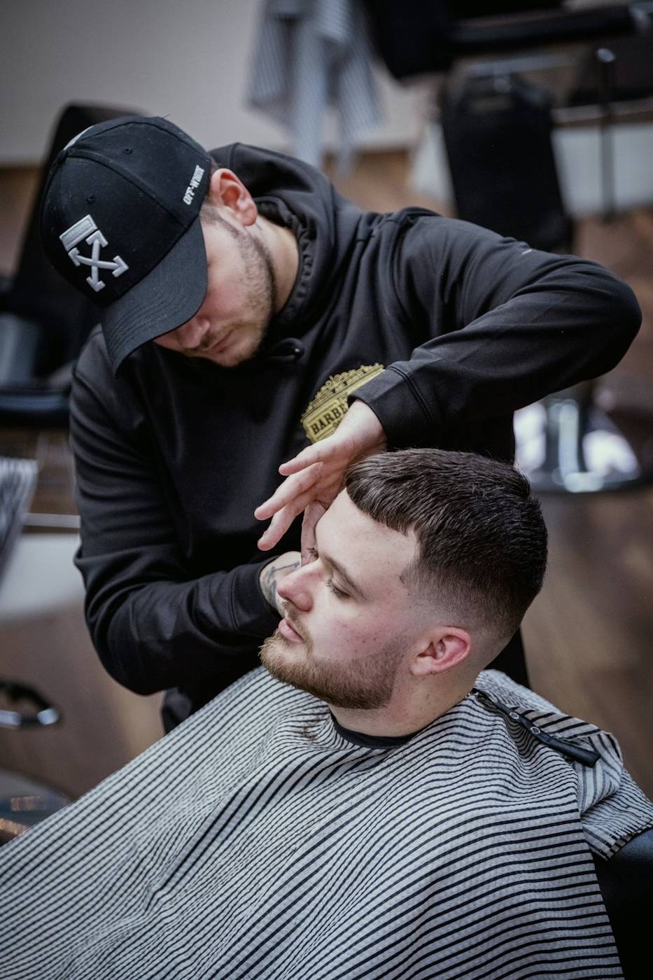 Barber in a cap working on a client’s beard line