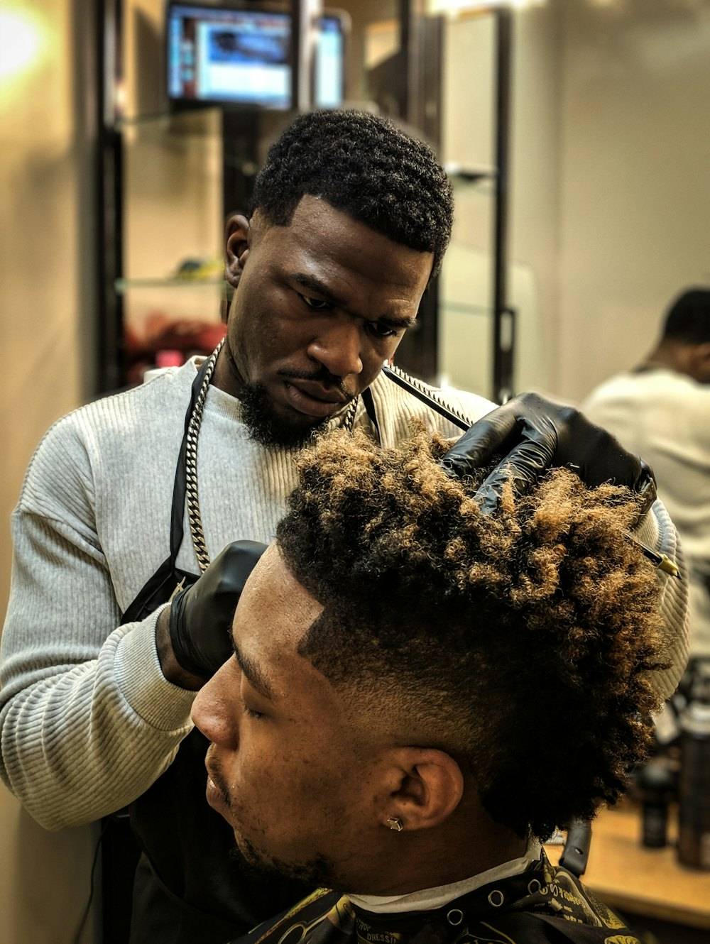 Barber shaping a client’s textured hair with a pick