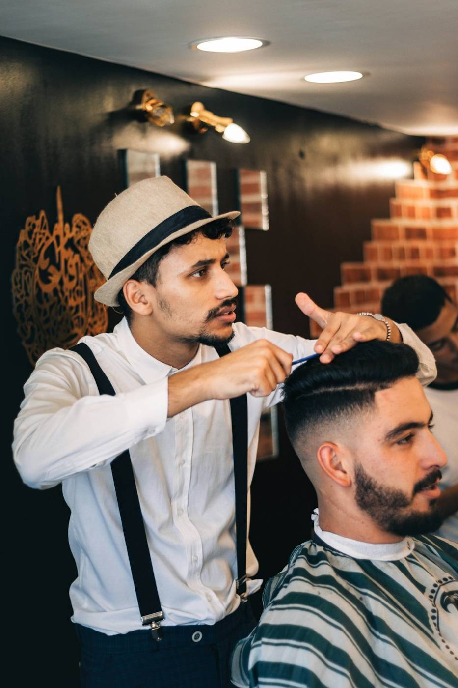 Barber in a white shirt and hat cutting a client’s hair