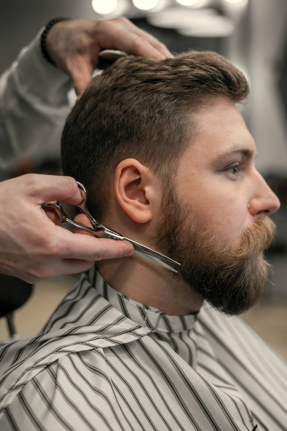 Barber shaping a full beard with shears