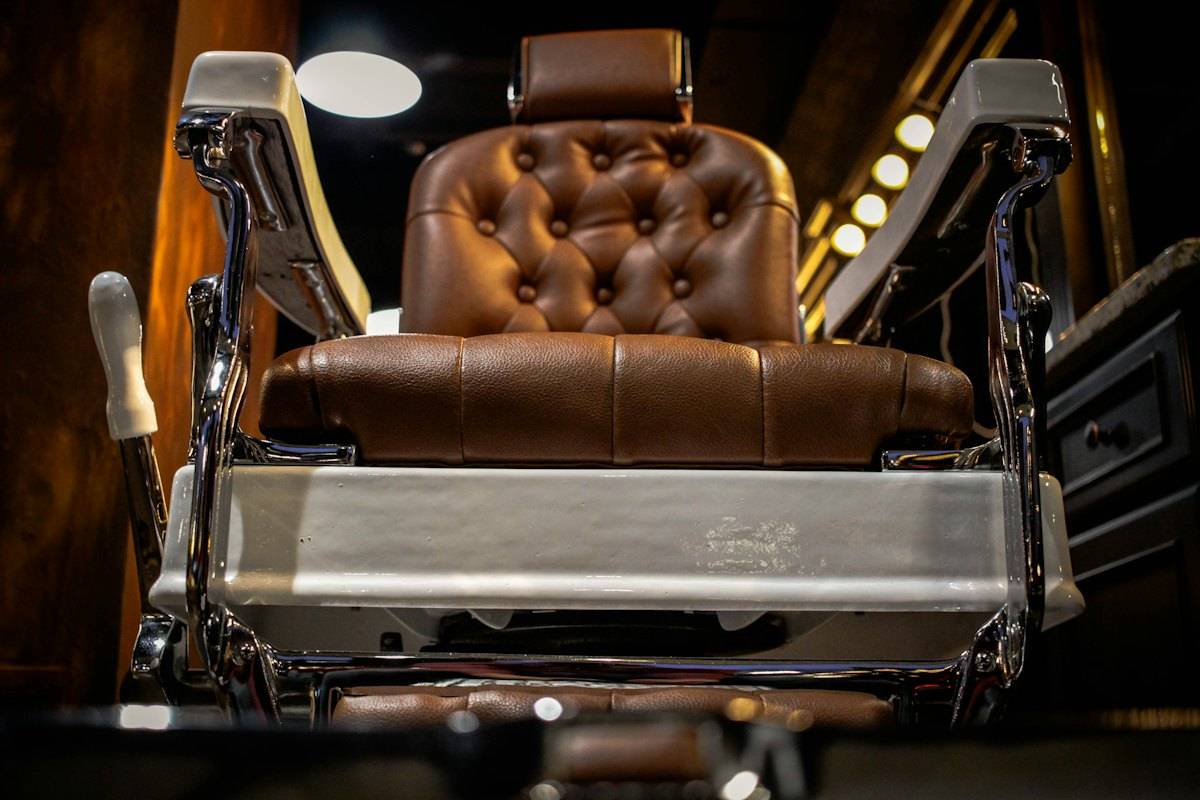 Tufted brown leather barber chair with chrome arms