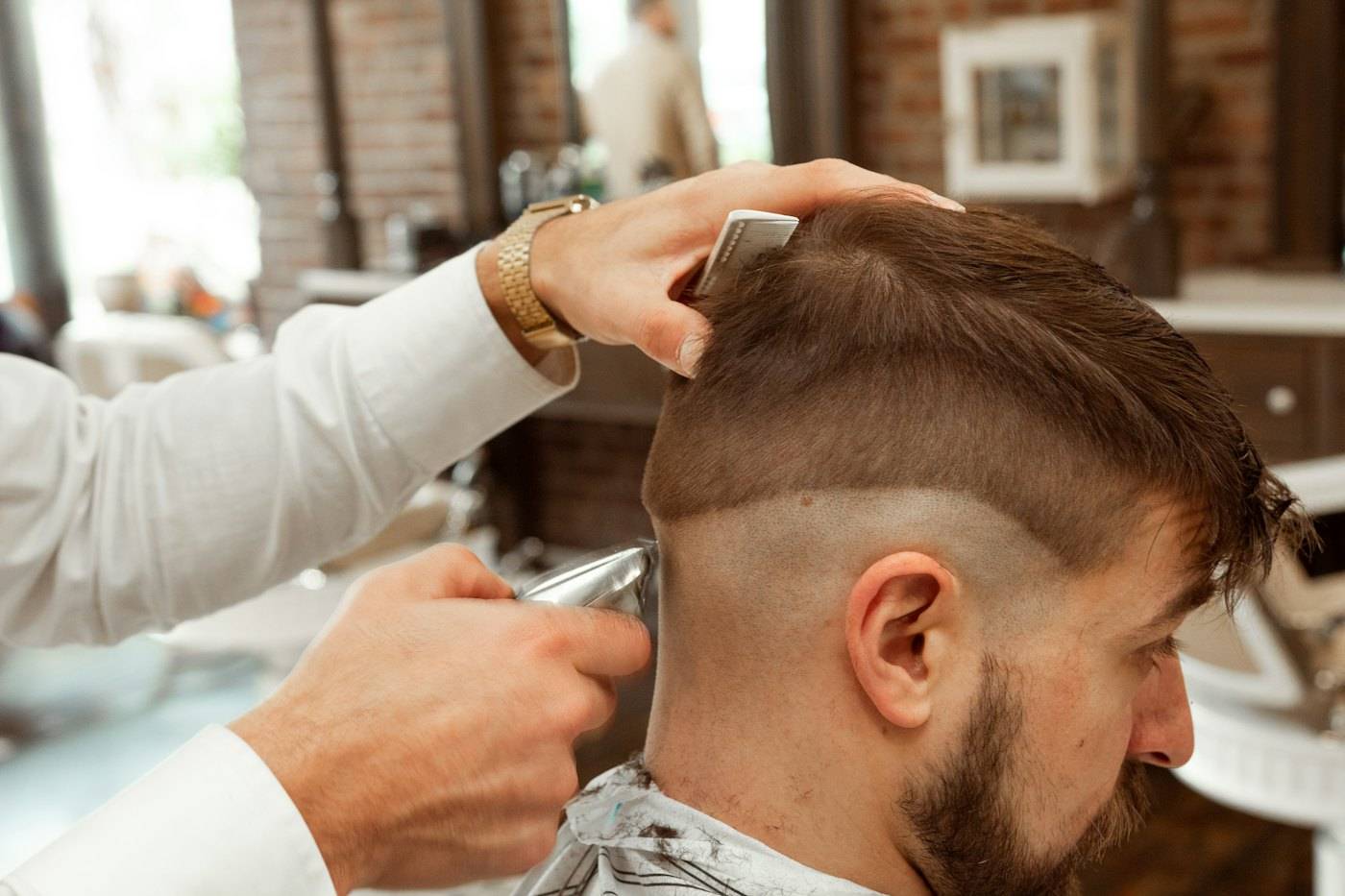 Barber cutting a skin fade with clippers and a comb