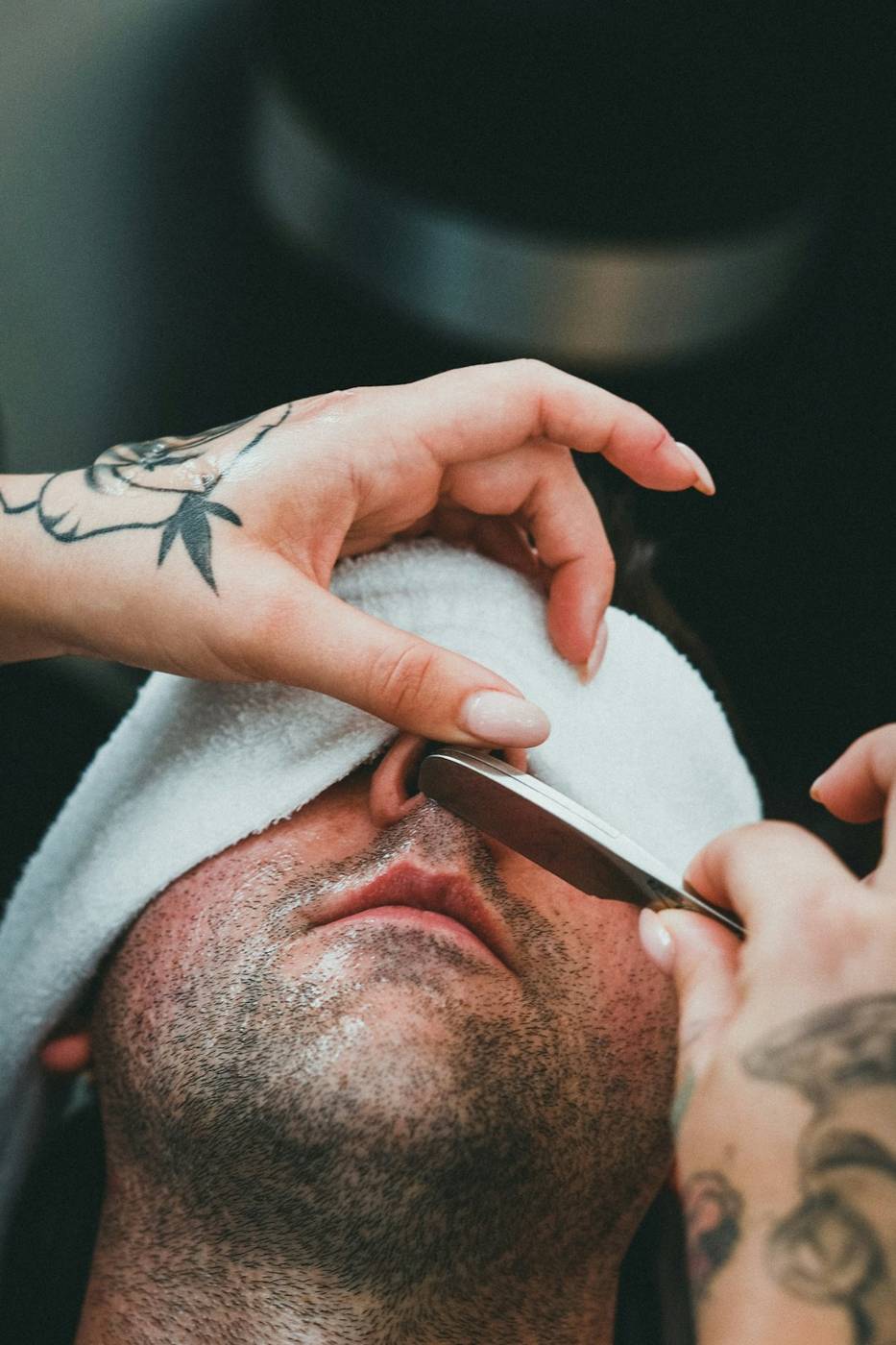 Barber pressing a hot towel over a client’s face