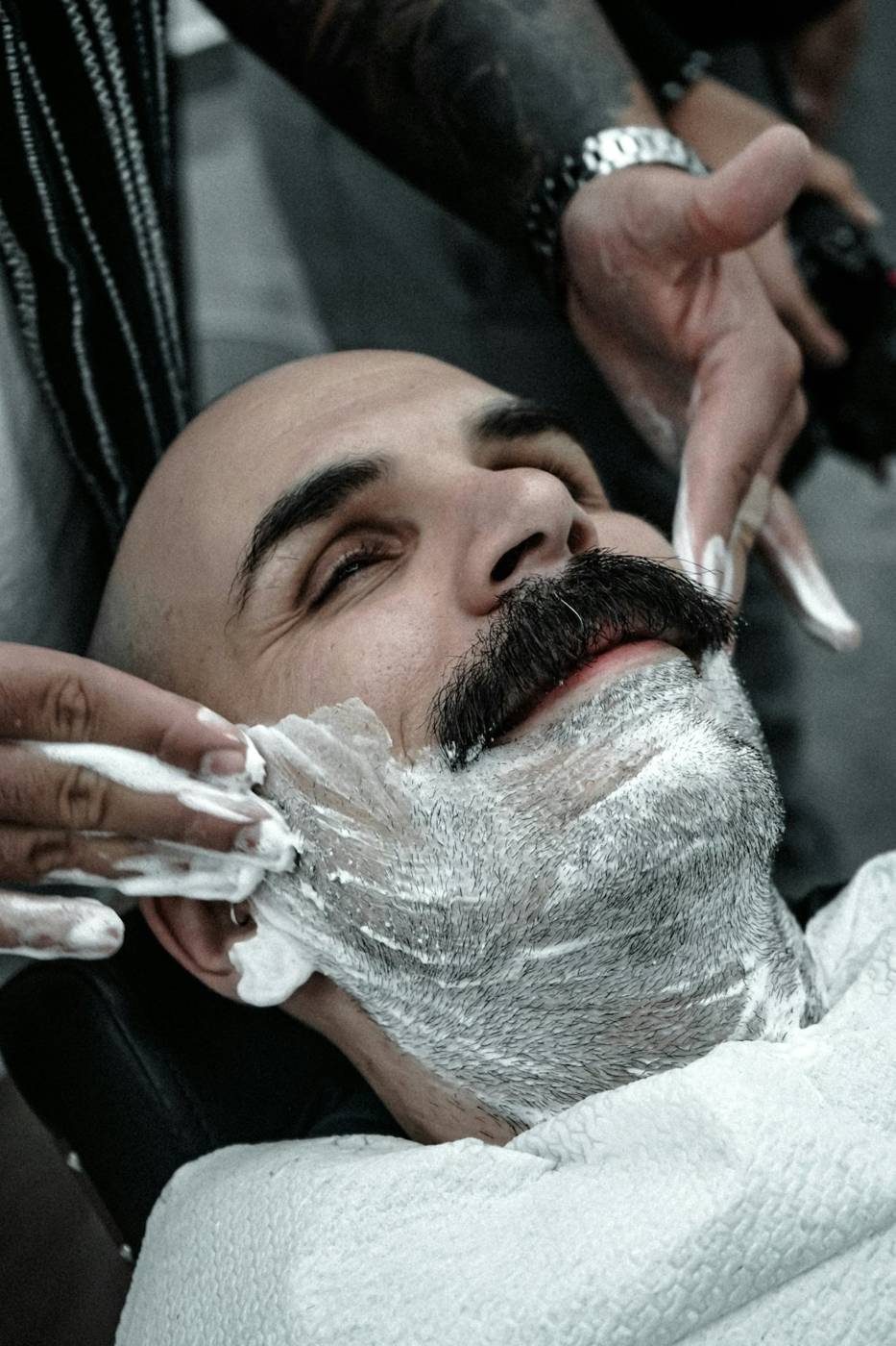 Barber shaving a smiling client with warm lather and a straight razor