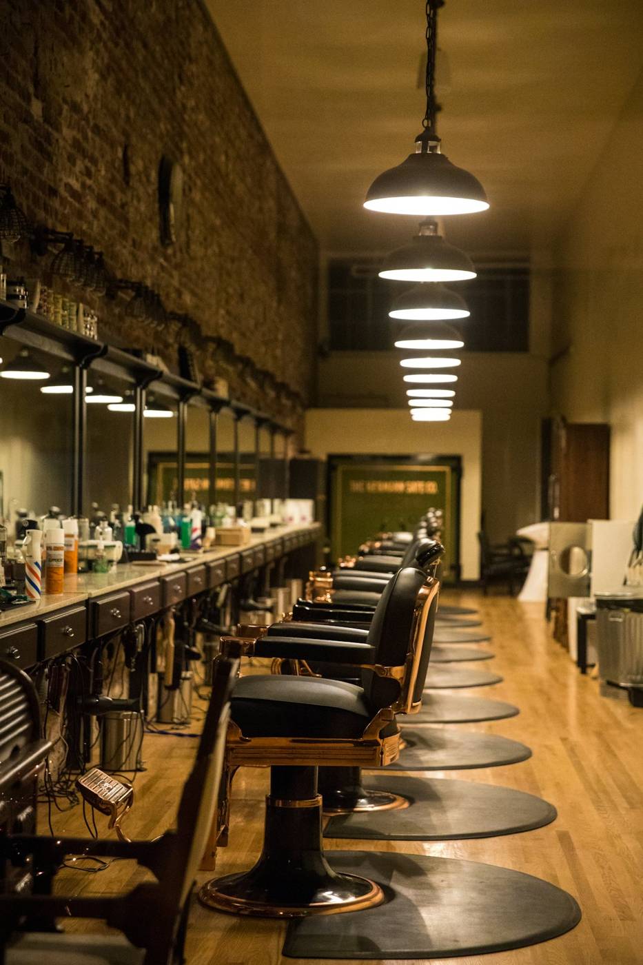 Long barber shop with a row of leather chairs under pendant lamps