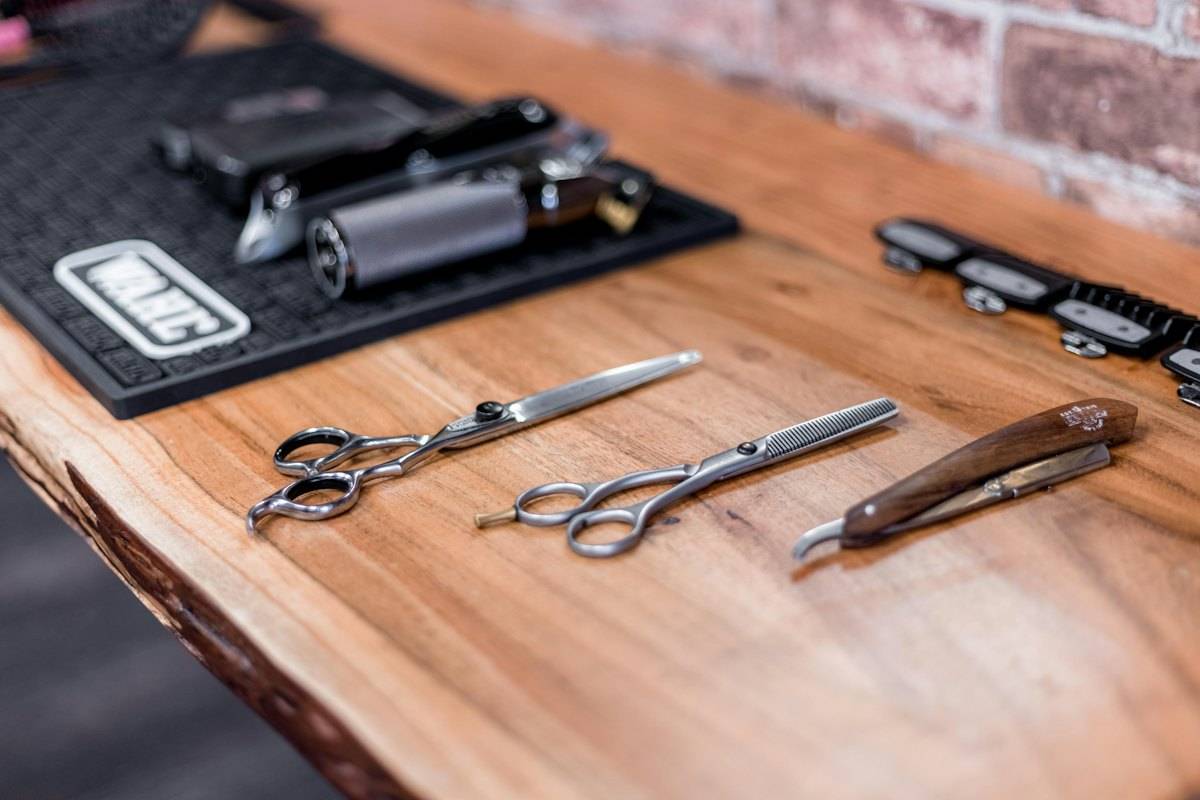 Shears and a straight razor laid out on a walnut counter