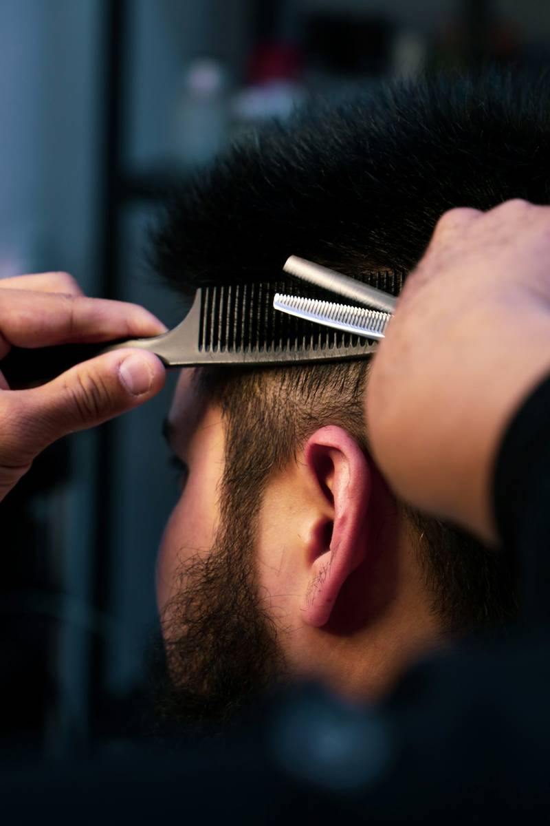 Barber trimming a client’s hair with thinning shears and a comb