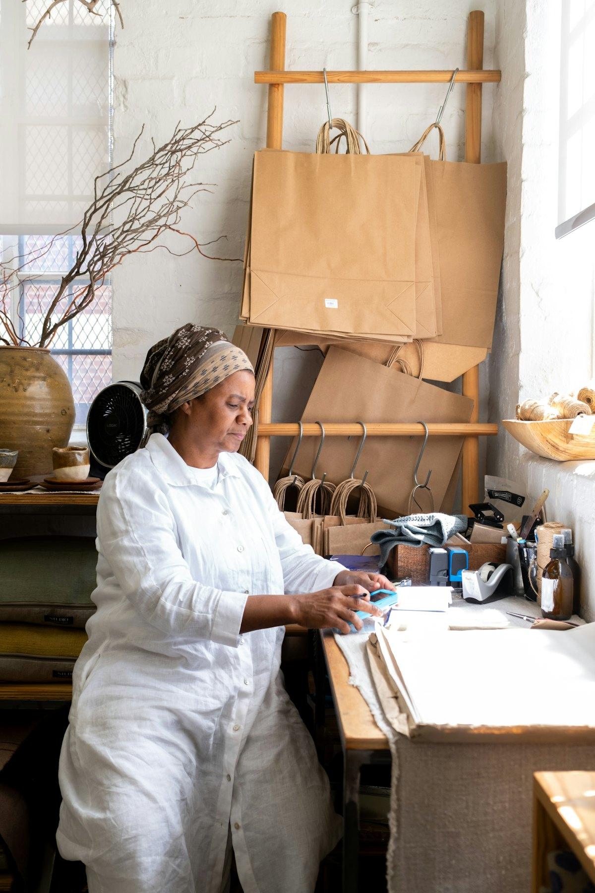 A woman in a white jacket working at a bench in a bright studio
