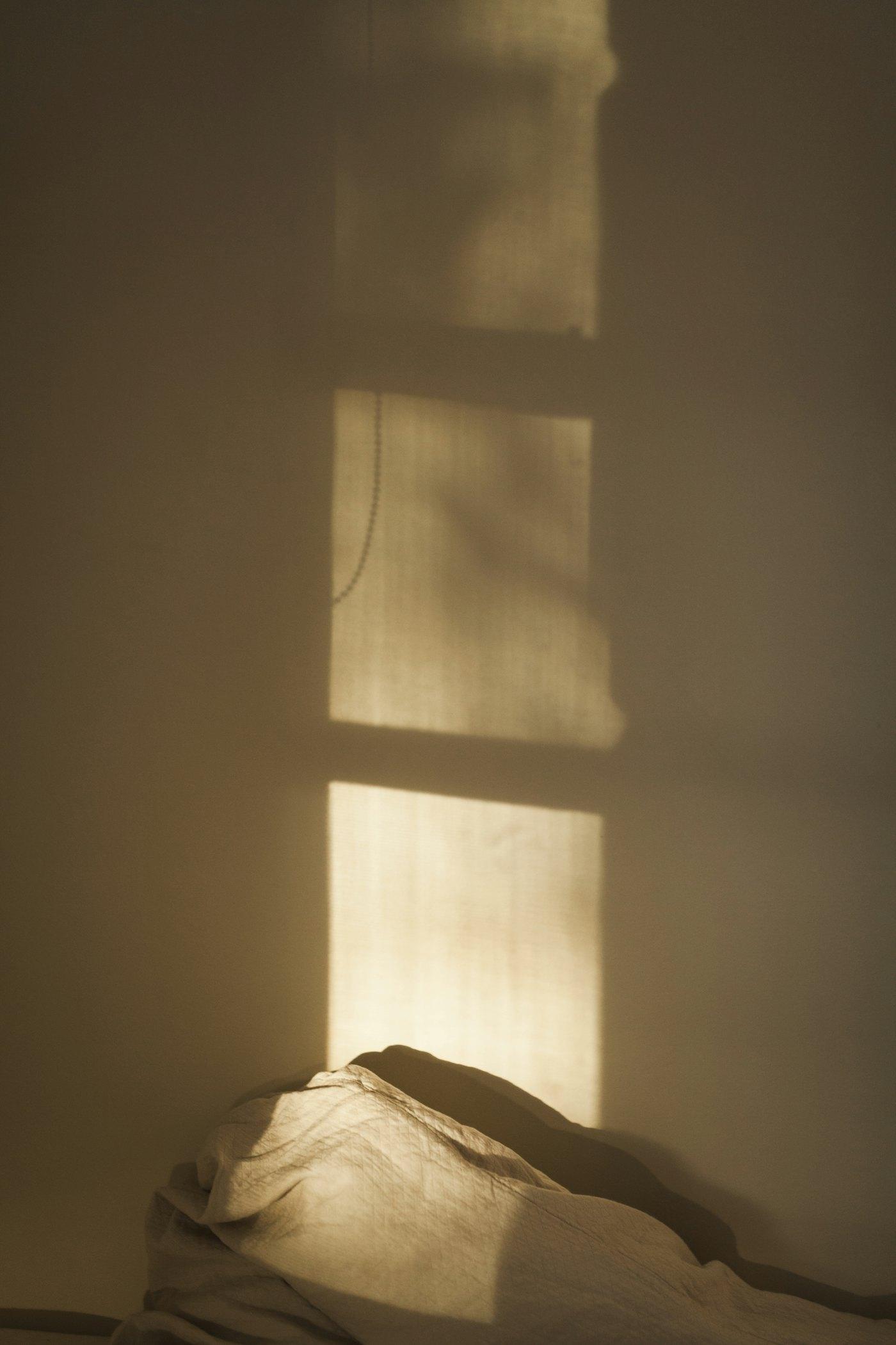 Soft evening light from a window falling across a plain wall