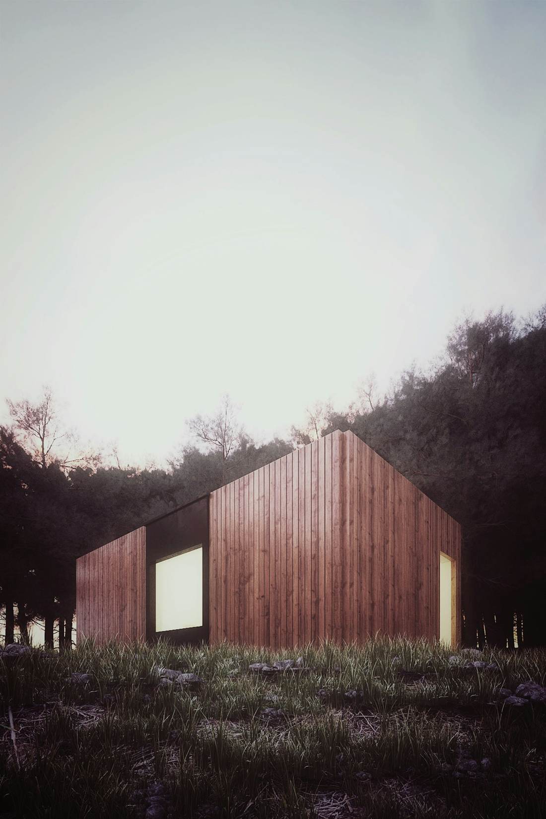 Timber barn-shaped home in an open field below a wooded hill