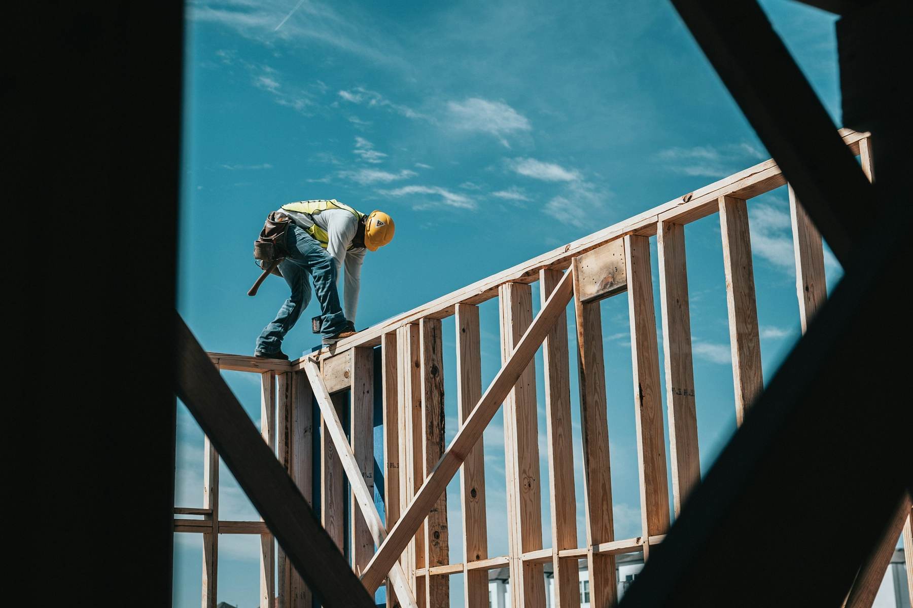 Builder on top of a new timber frame against a blue sky