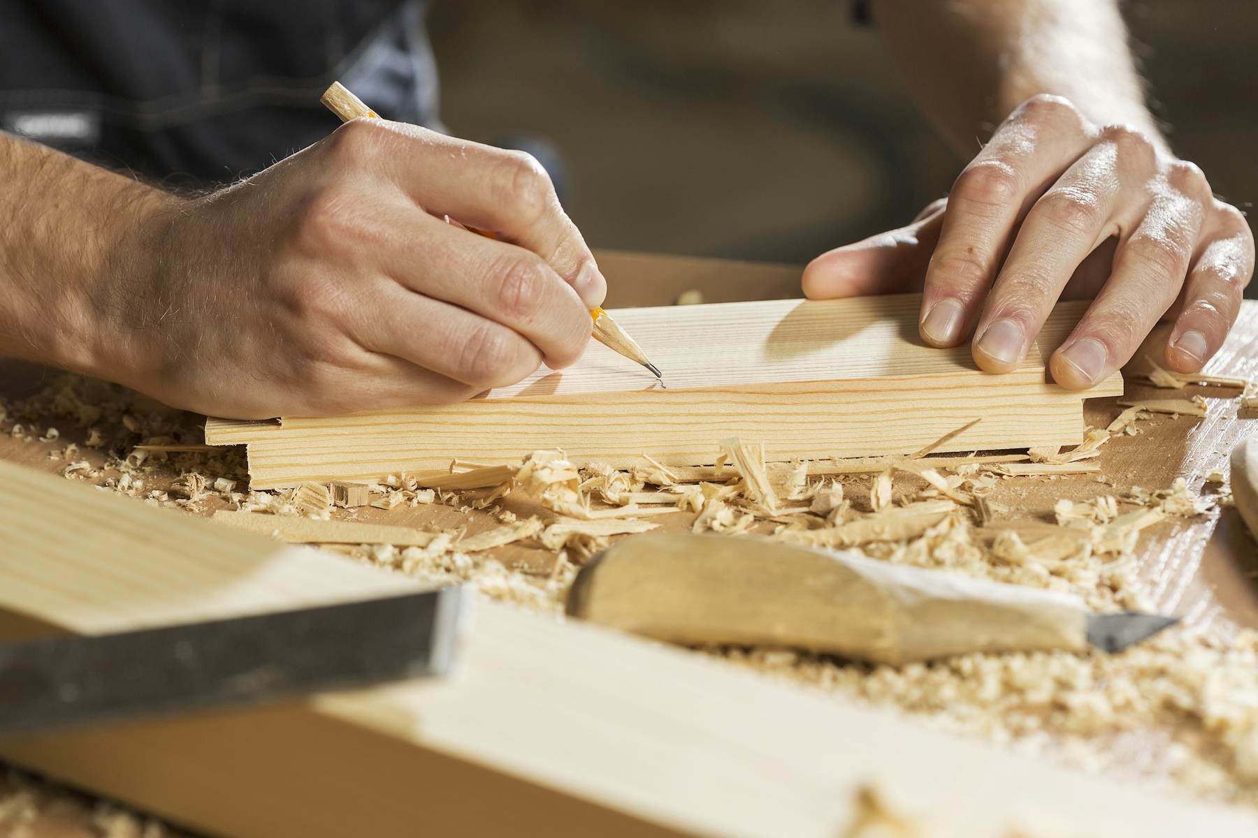 Carpenter marking a timber board with a pencil