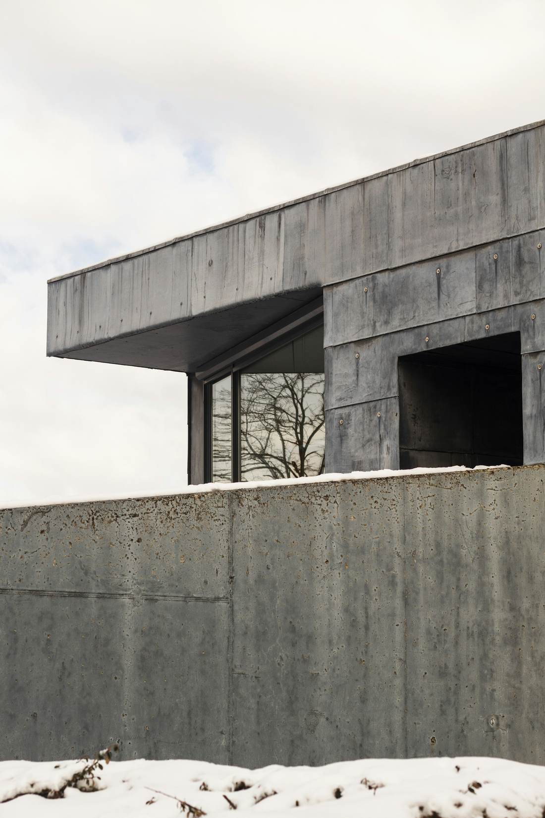 Board-formed concrete house with a cantilevered upper floor