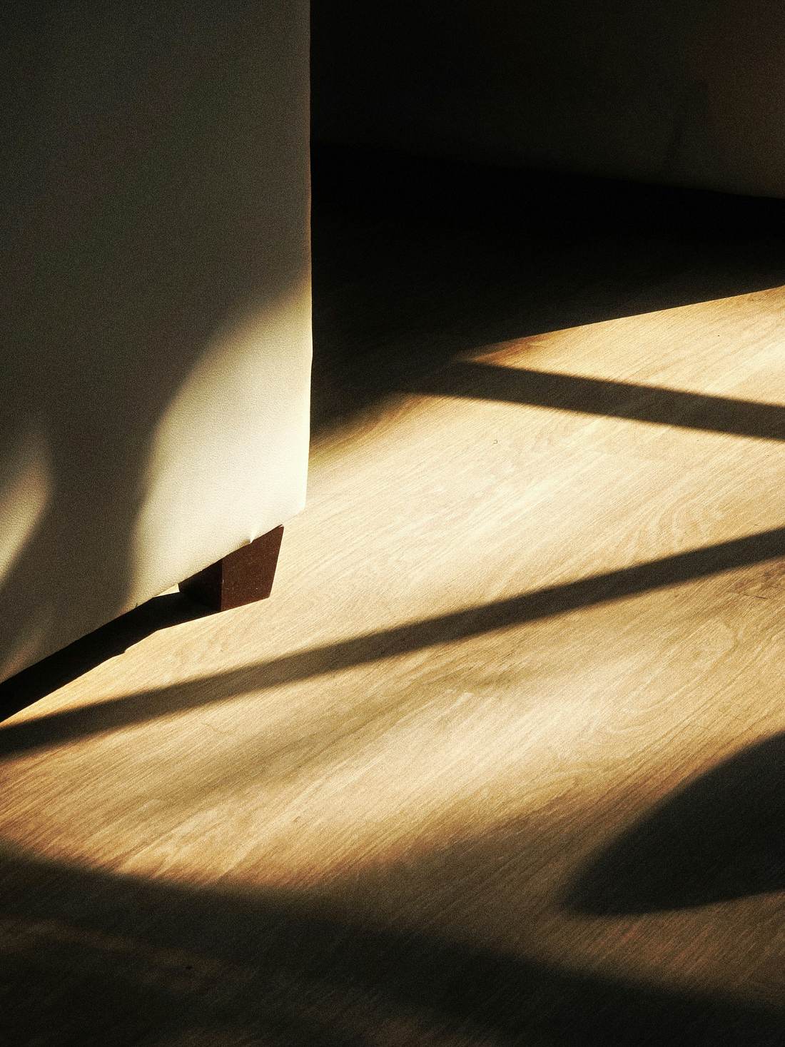 Late sun falling across an oak floor and a plaster wall