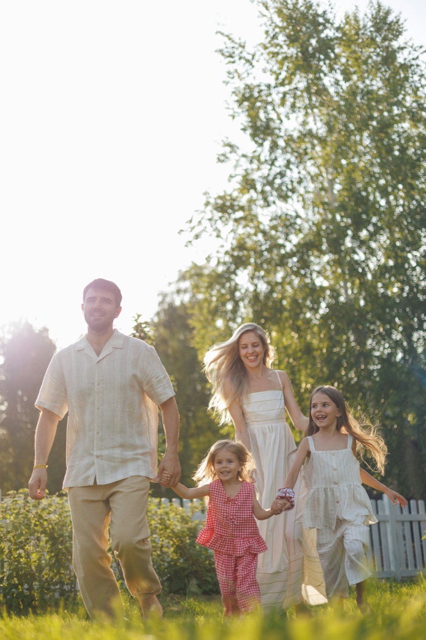 A family running together through a sunny garden
