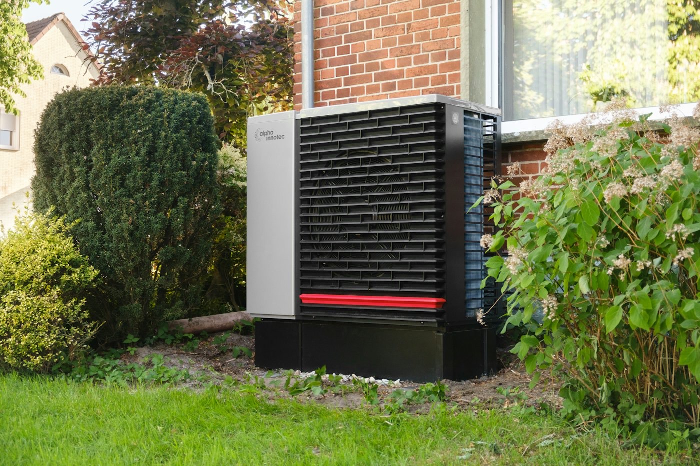 Outdoor unit beside a brick wall with green shrubs
