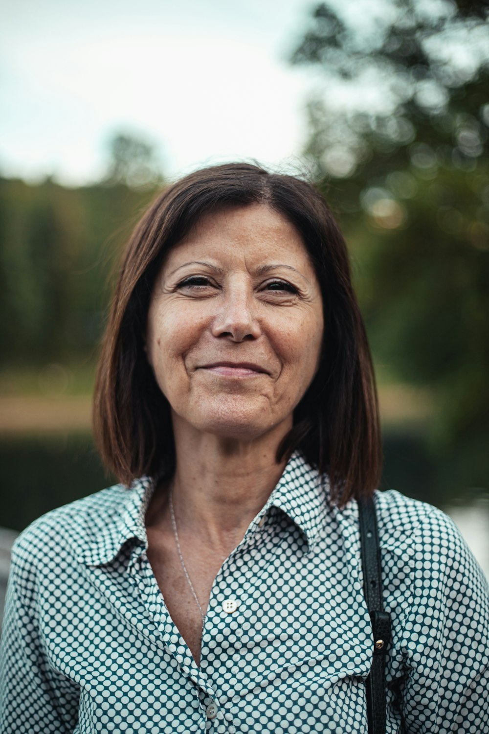 Lena Moretti, co-owner, smiling outdoors in a teal checked shirt