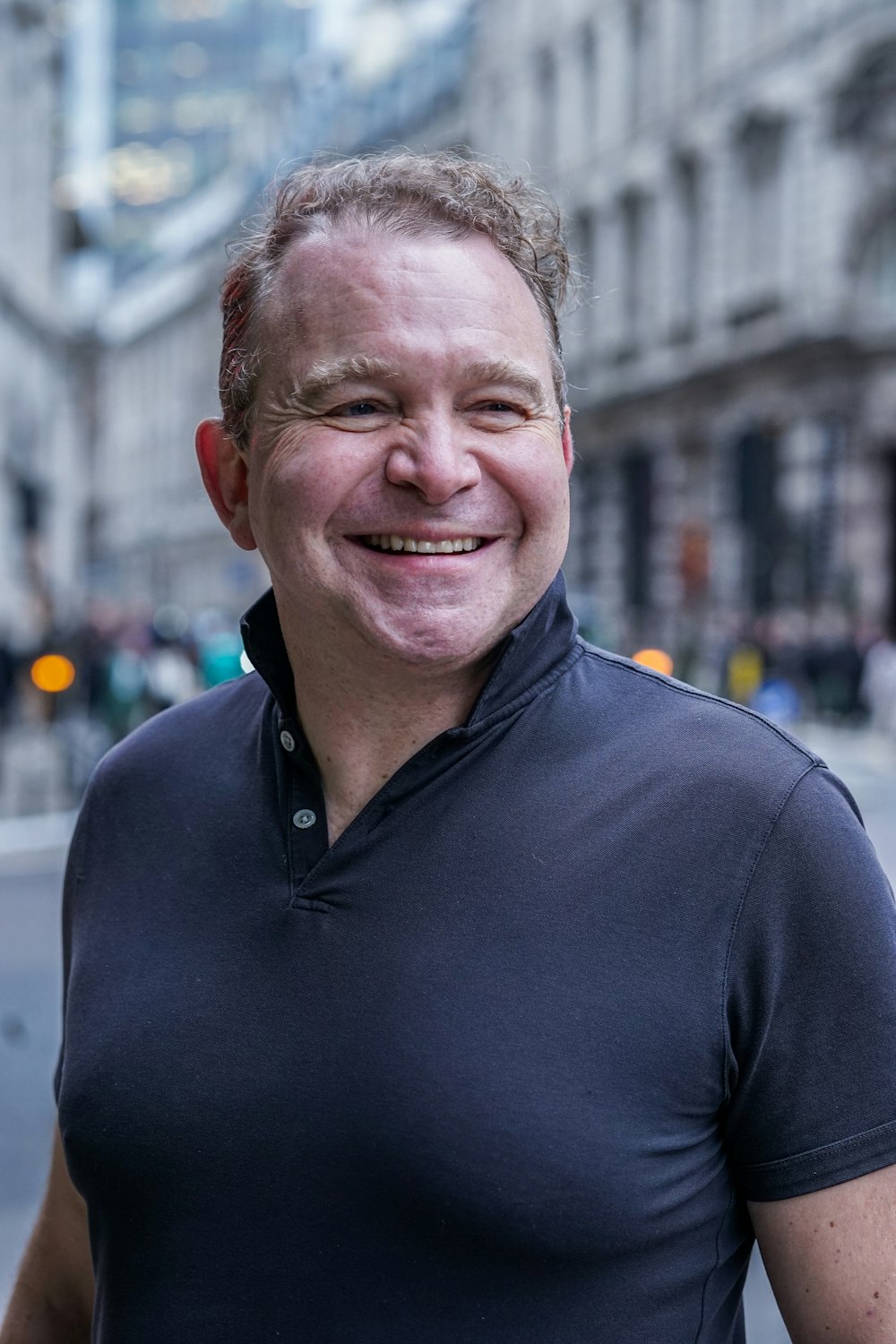 Tom Moretti, co-owner, smiling on a city street in a navy polo shirt