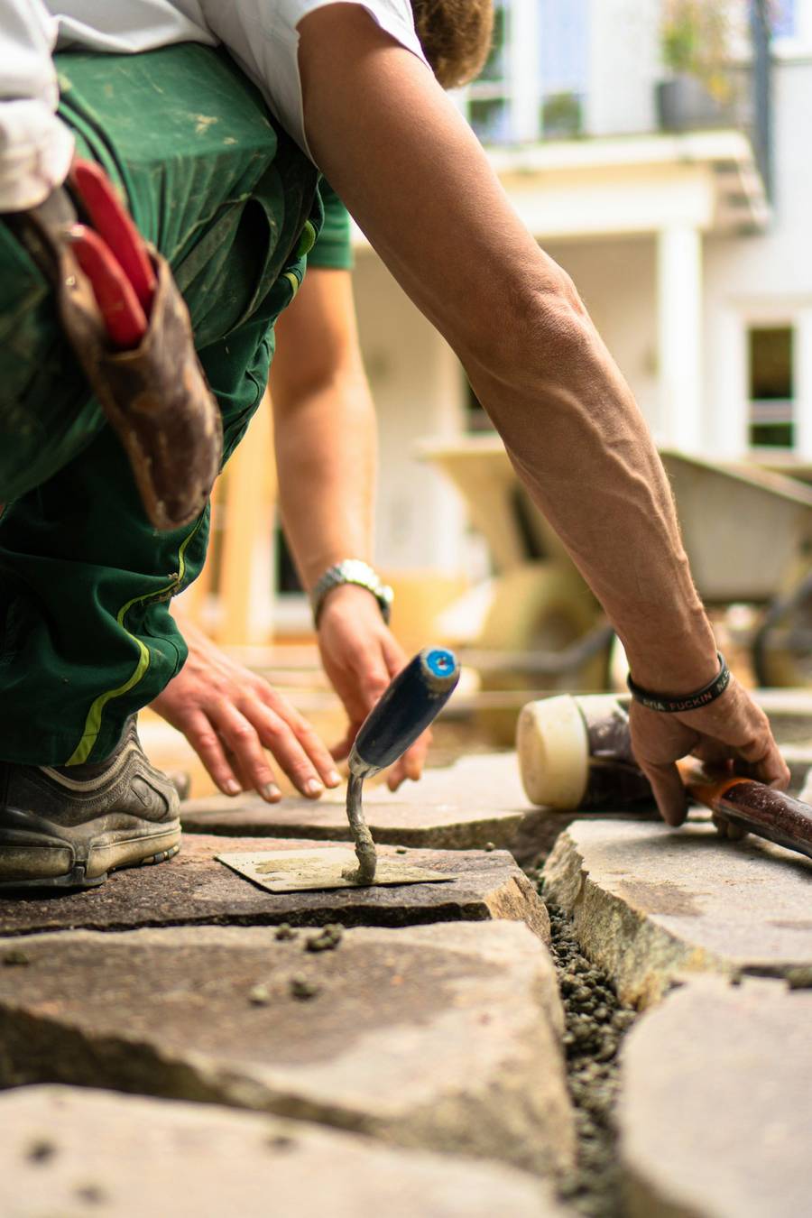 A landscaper setting a stone slab into a bed of sand