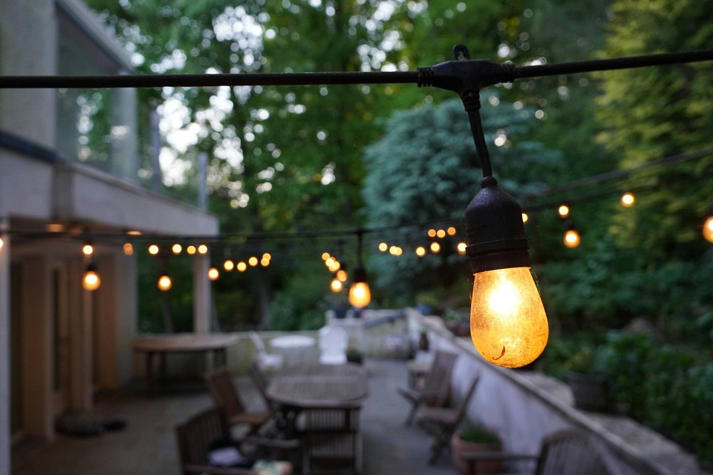 String lights glowing over a patio at dusk