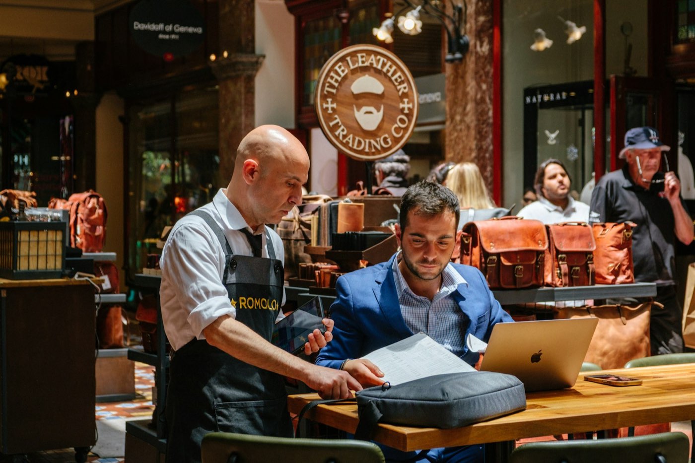 Two business owners reviewing paperwork and a laptop together in their shop