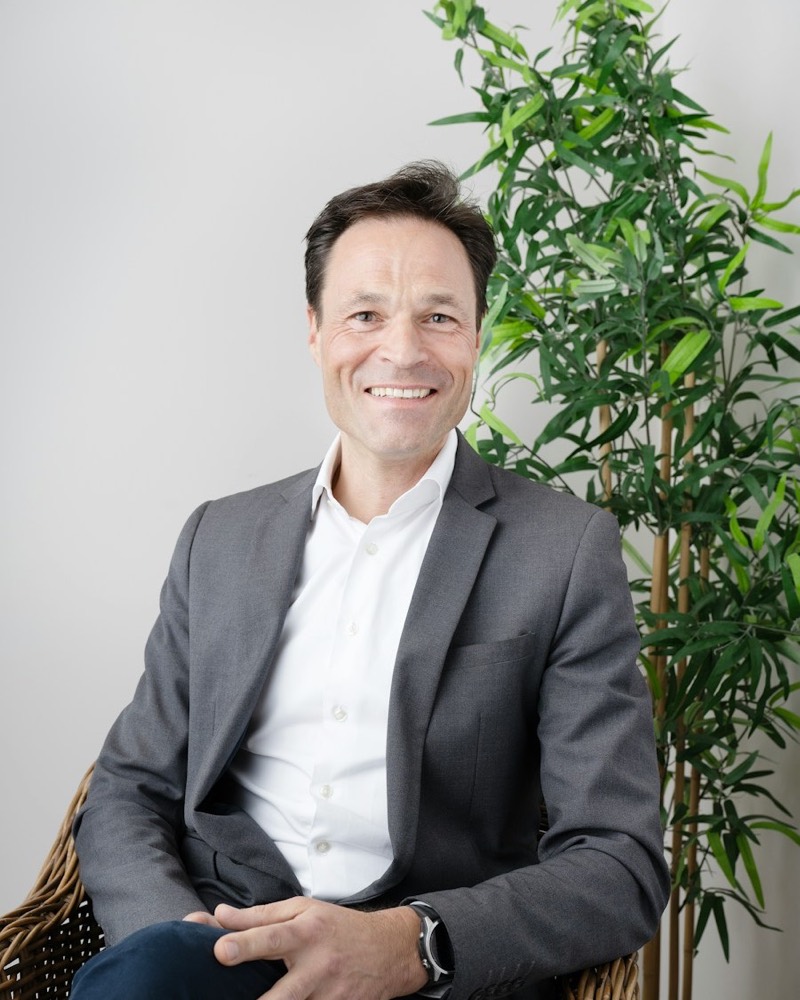 Portrait of Graham Whitlock, smiling, in a gray suit jacket