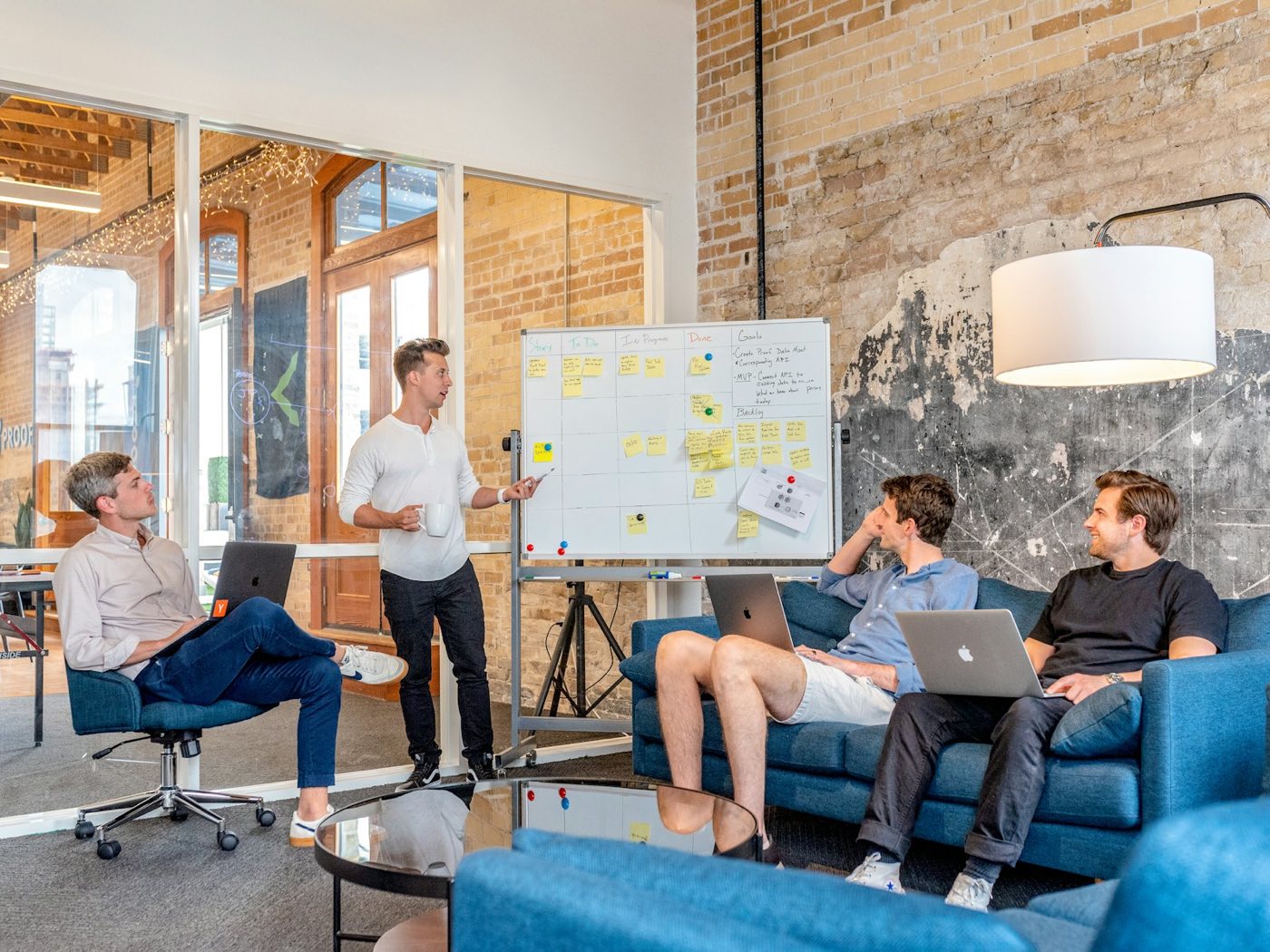 A small team in a brick-walled room working through a plan on a whiteboard