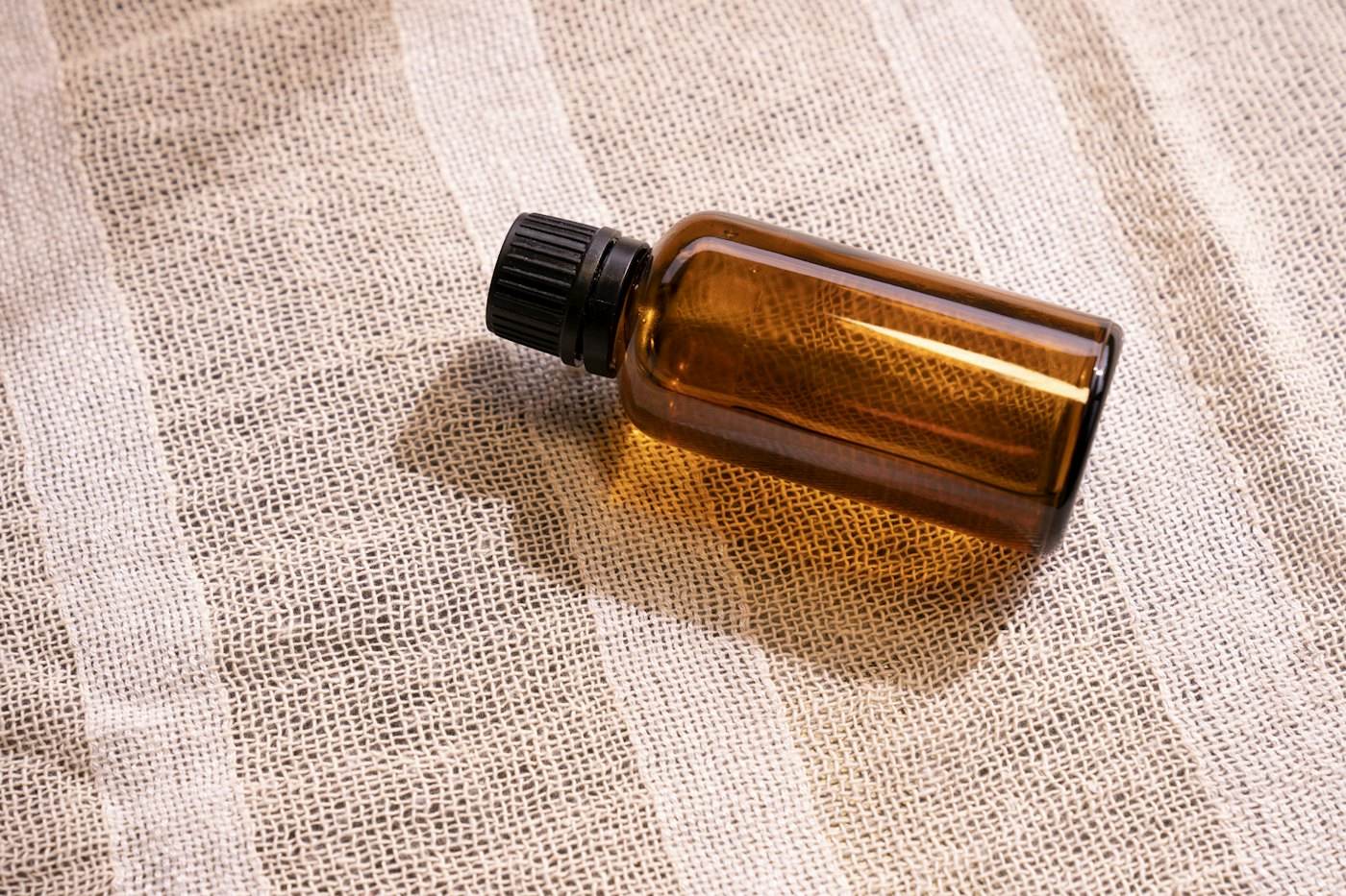 An amber glass bottle resting on soft linen