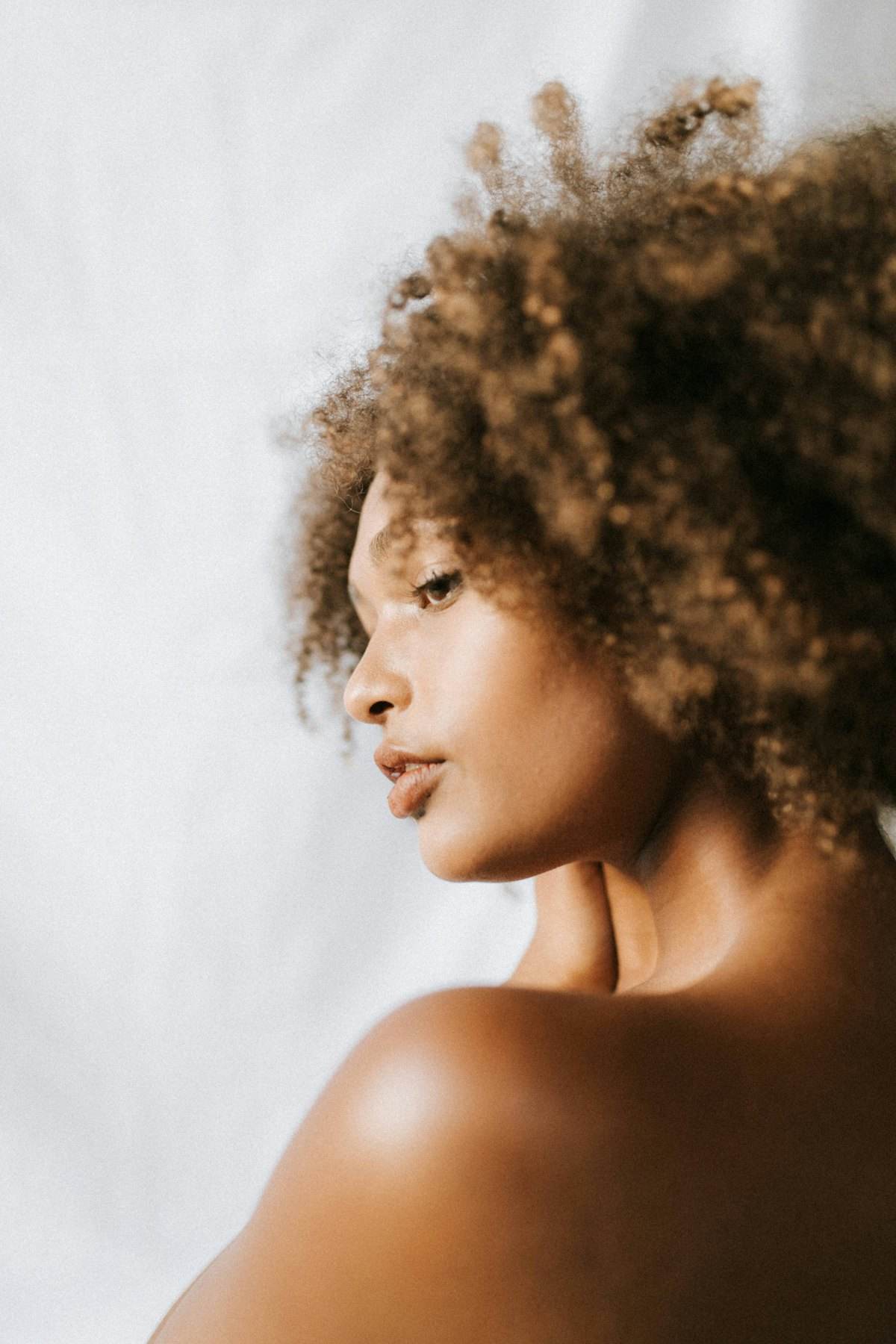 Woman with curly hair looking to the side in soft light