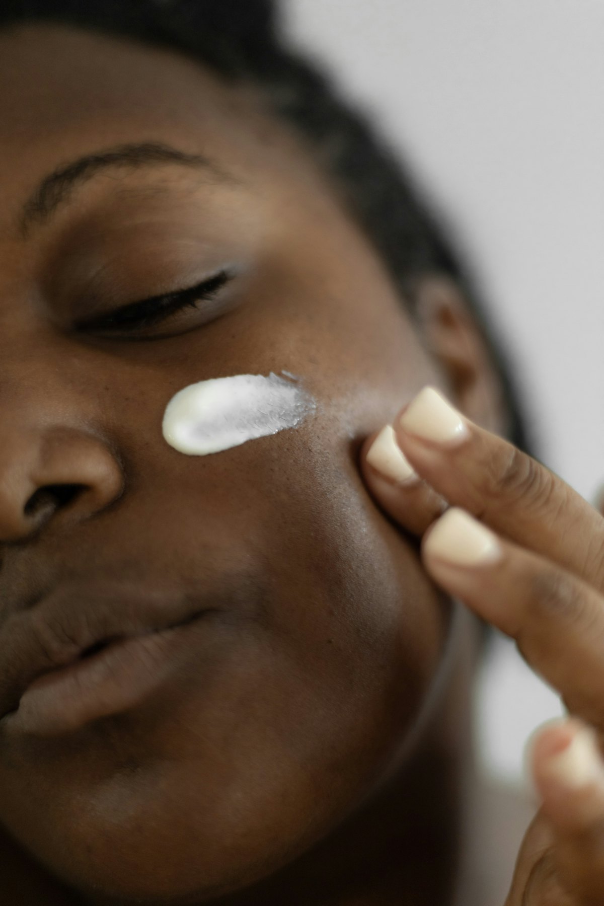 A woman smoothing moisturizer onto her cheek
