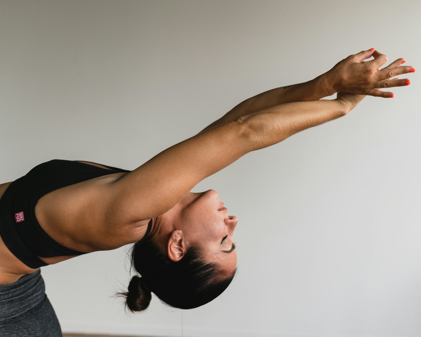 A woman reaching her arms long overhead with her eyes closed