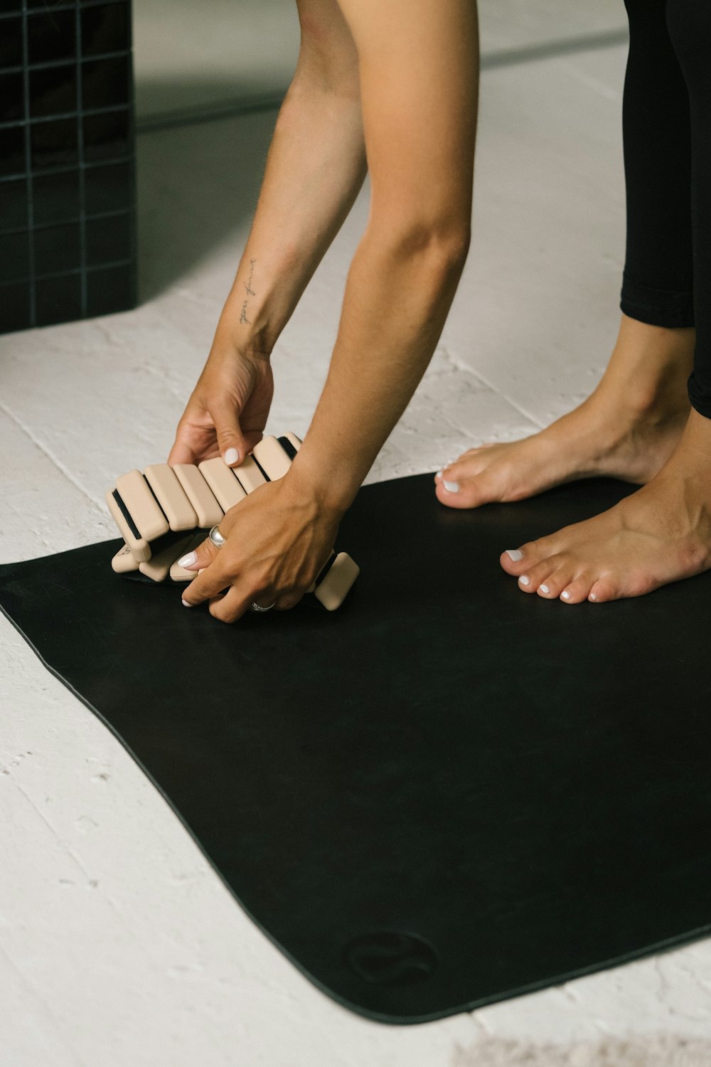 Bare feet and hands meeting on a dark mat