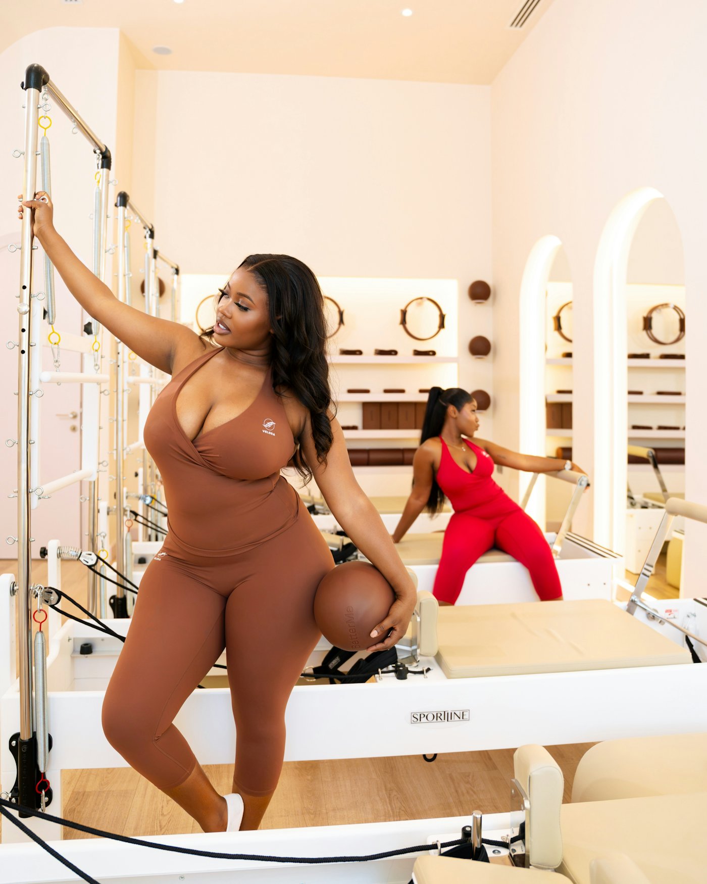 A woman with a Pilates ball beside the reformer tower
