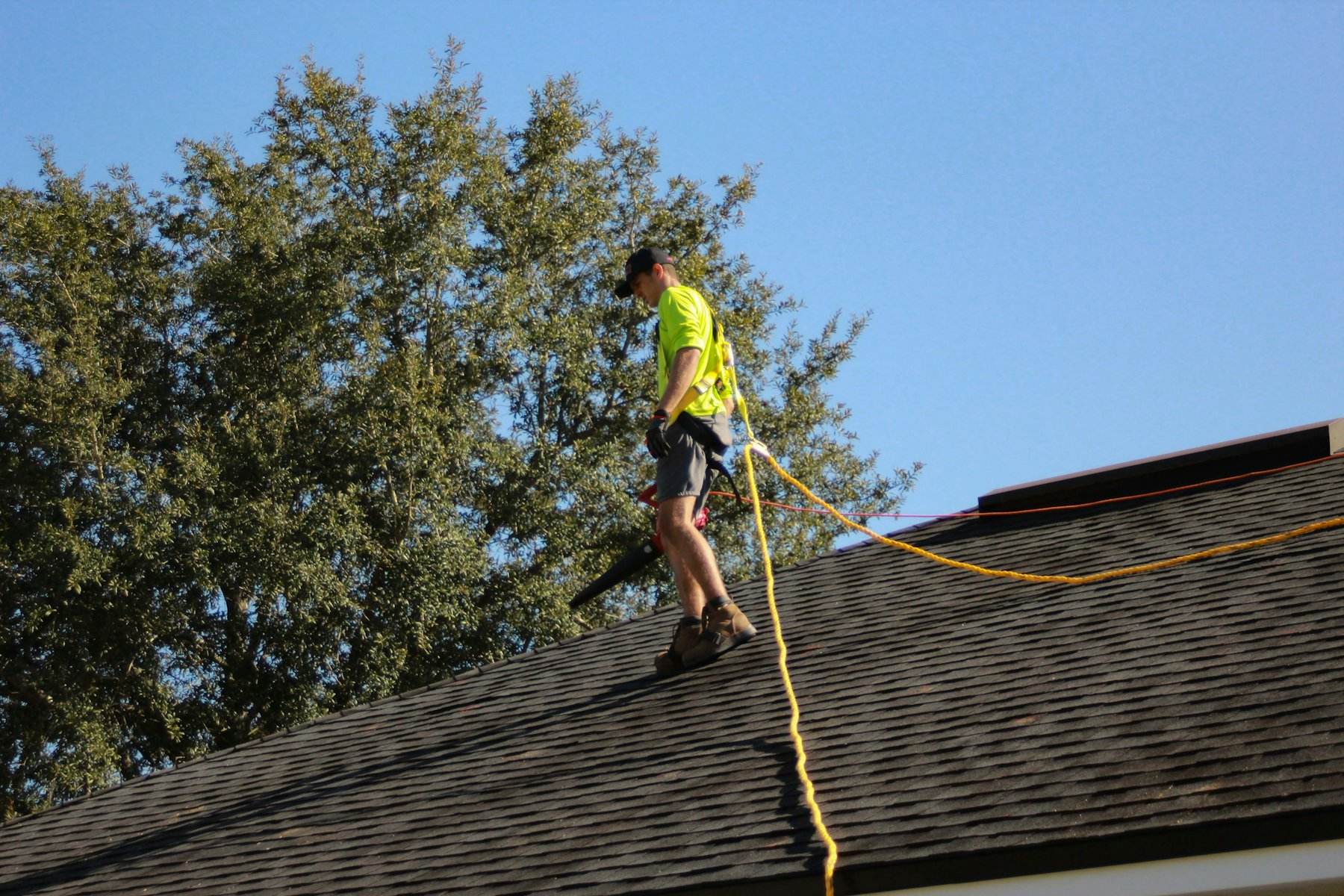 Roofer tied off with a safety rope on a pitched roof
