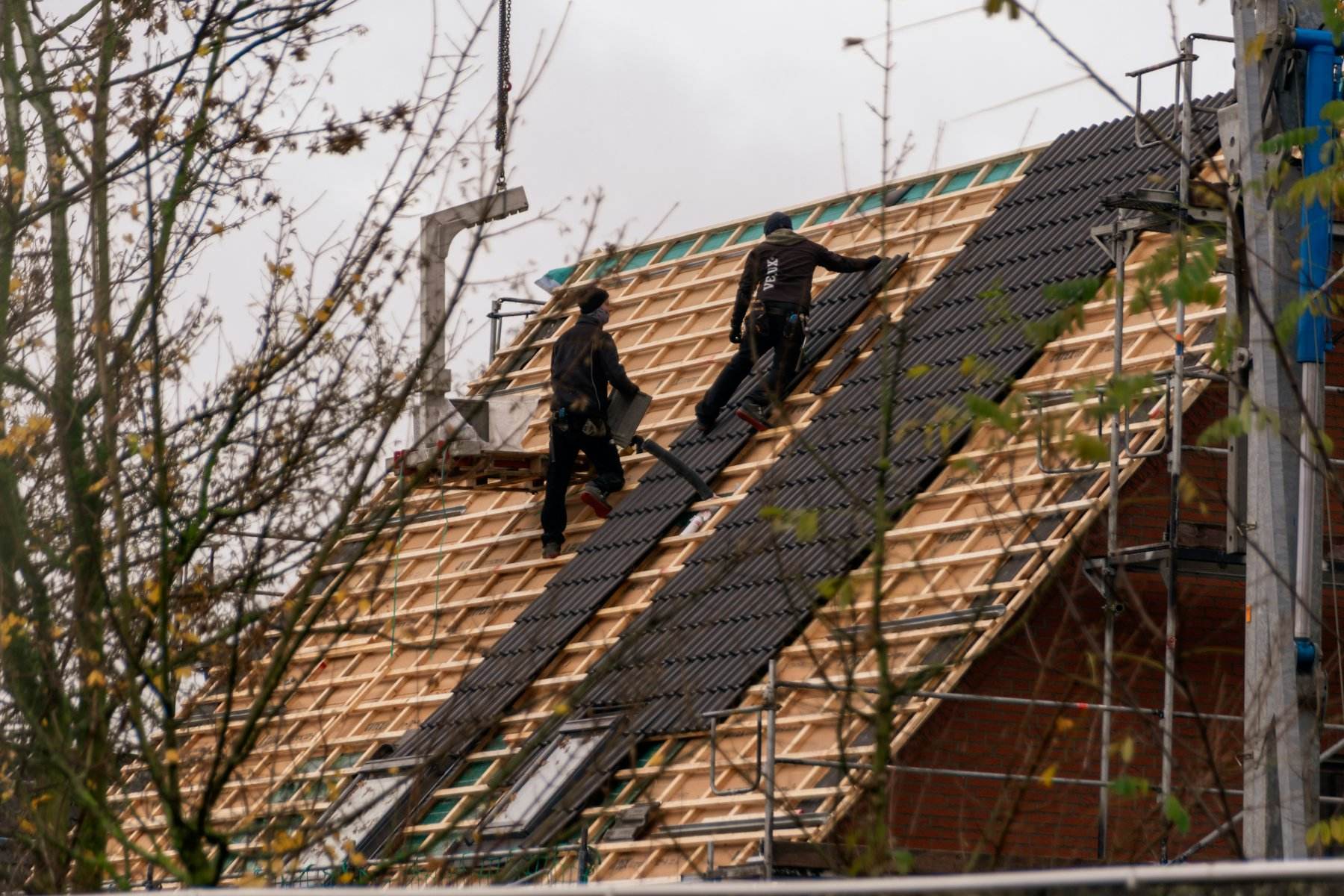 Roofers laying new shingles on a steep roof