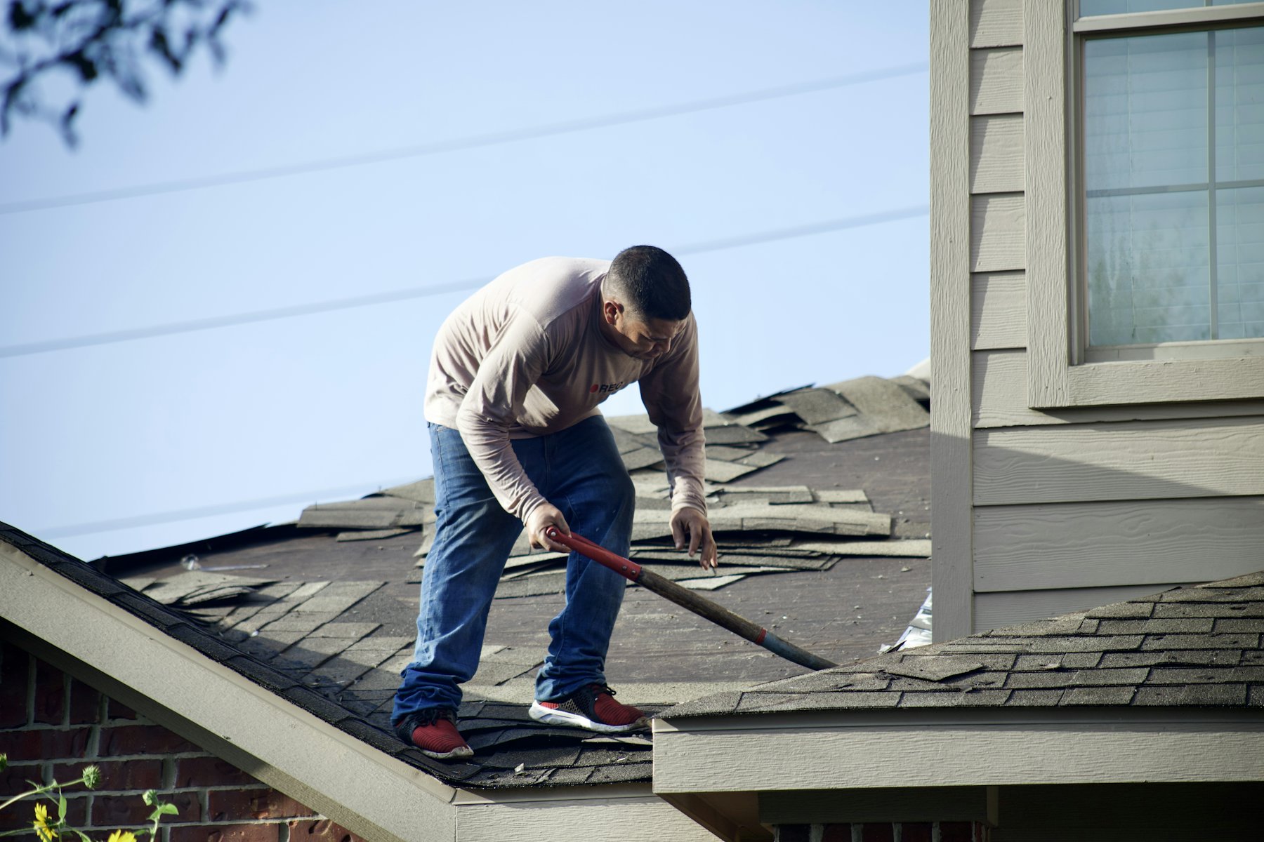 Roofer removing storm-damaged shingles