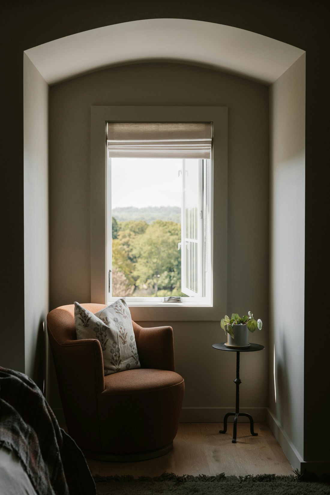 A soft armchair beside a tall window with a garden view