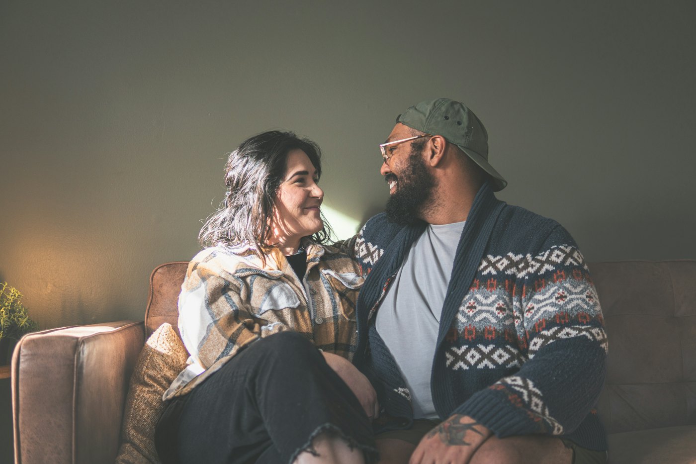 A couple sitting close together on a sofa, smiling and talking