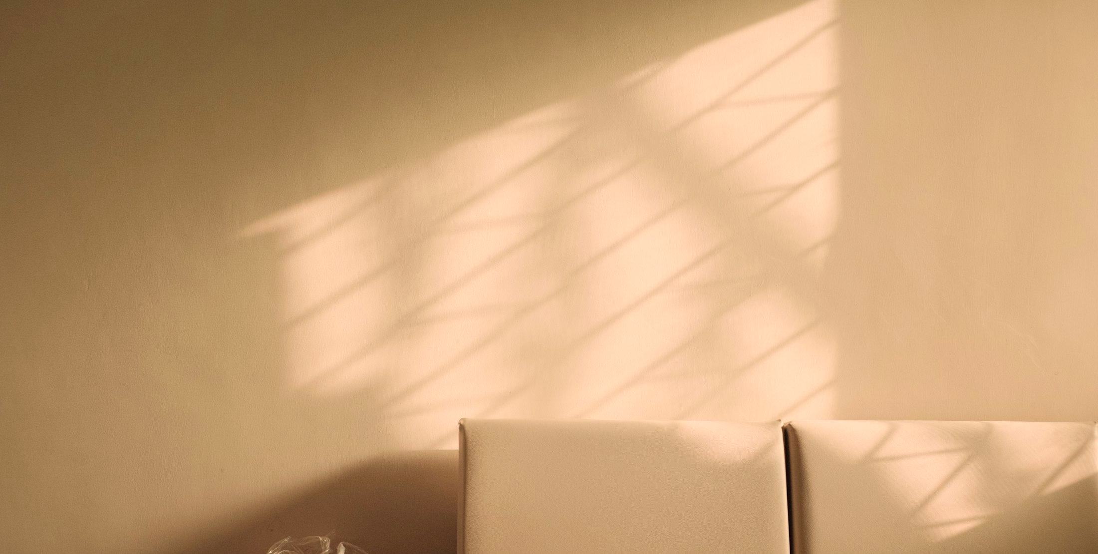 Late afternoon sunlight falling across a warm wall above a cream sofa