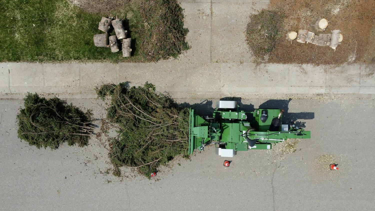 Seen from above, branches being fed into a wood chipper on a street