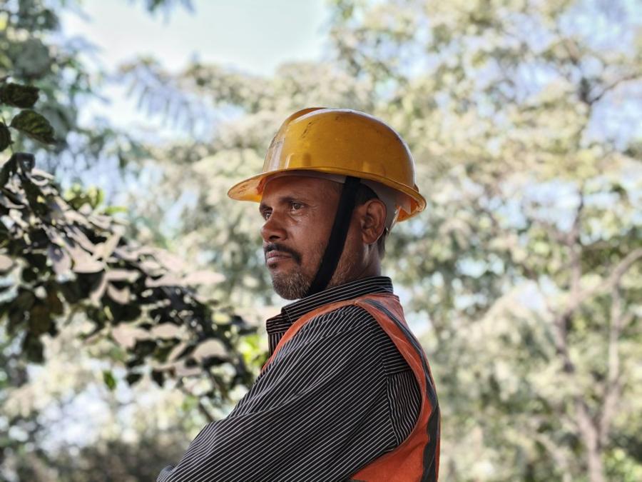 A crew member in a yellow hard hat and orange safety vest